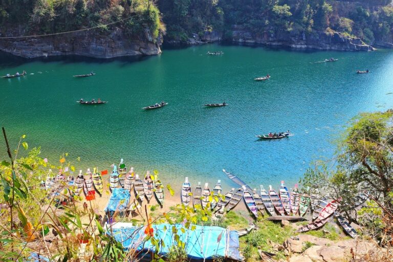 A wooden boat floating over the crystal-clear waters of Umngot River in Dawki, Meghalaya
