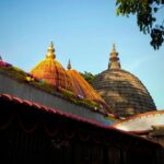 Kamakhya Temple’s red dome and carvings surrounded by lush greenery in Guwahati.